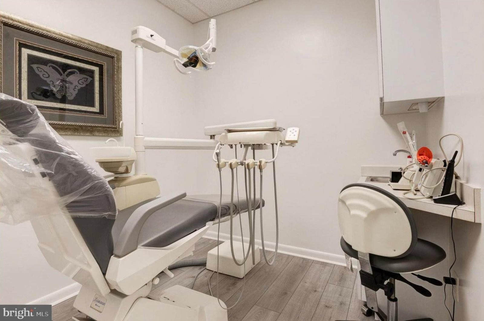 Private treatment room with a modern dental chair and framed butterfly artwork